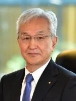 眼鏡をかけたシニアの日本人男性が、紺色のスーツと青いネクタイを着用し、カメラをまっすぐ見つめているポートレート写真