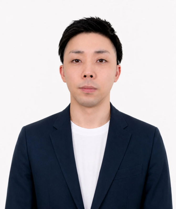 白い背景の前で紺色のジャケットと白いTシャツを着た若いアジア人男性の上半身ポートレート。男性は短髪で、カメラをまっすぐ見つめ、真顔で写っています。