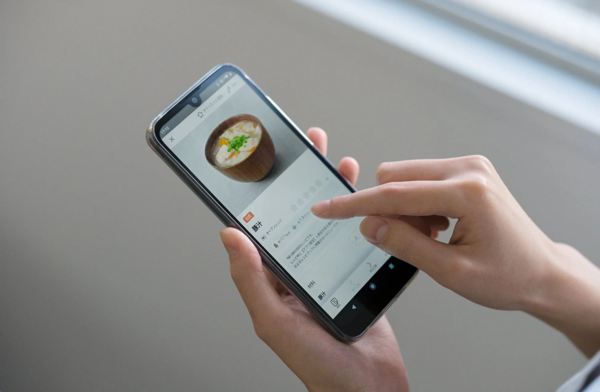 スマートフォンで豚汁のレシピが表示された料理アプリを操作している手元のクローズアップ