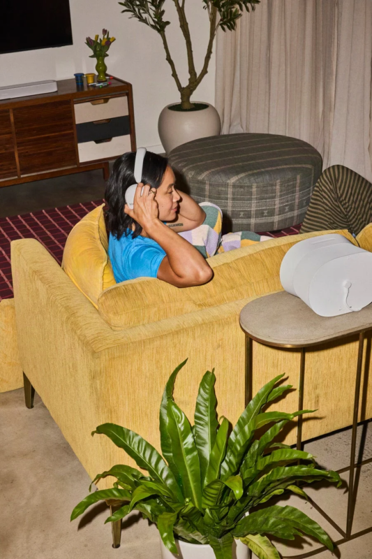 ソファでSonos Ace Ultraヘッドホンを着用してリラックスする女性
